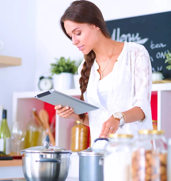 Mujer joven usando una tableta para cocinar en su cocina — Foto de Stock