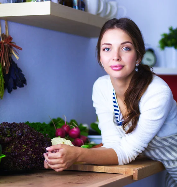 Mujer joven de pie cerca de escritorio en la cocina — Foto de Stock