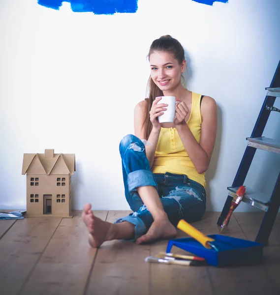 Portrait of female painter sitting on floor near wall after painting — Stock Photo, Image