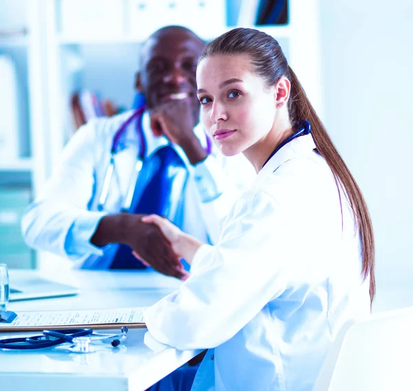 Zwei glücklich lächelnde junge Mediziner beim Händeschütteln im Büro — Stockfoto