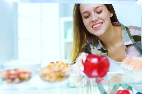 Ritratto di femmina in piedi vicino al frigorifero aperto pieno di cibo sano, verdure e frutta. Ritratto di femmina — Foto Stock