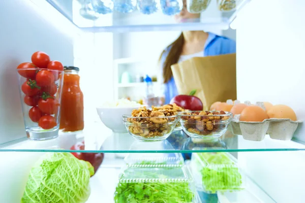 Portrait of female standing near open fridge full of healthy food, vegetables and fruits. Portrait of female — Stock Photo, Image