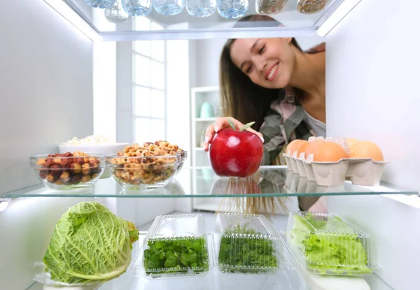 Portrait of female standing near open fridge full of healthy food, vegetables and fruits. Portrait of female — Stock Photo, Image