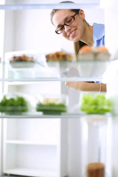 Retrato de fêmea em pé perto da geladeira aberta cheia de alimentos saudáveis, legumes e frutas. Retrato de fêmea — Fotografia de Stock