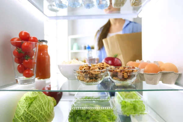 Portrait of female standing near open fridge full of healthy food, vegetables and fruits. Portrait of female — Stock Photo, Image