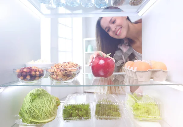 Portrait of female standing near open fridge full of healthy food, vegetables and fruits. Portrait of female — Stock Photo, Image