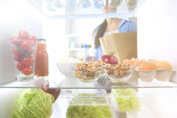 Portrait of female standing near open fridge full of healthy food, vegetables and fruits. Portrait of female — Stock Photo, Image