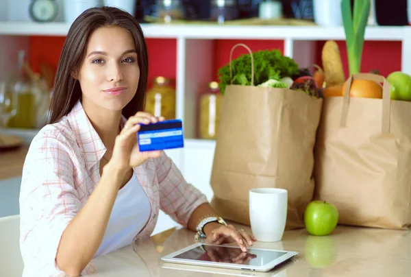 Una giovane donna in cucina, che usa il suo iPad. Giovane donna — Foto Stock