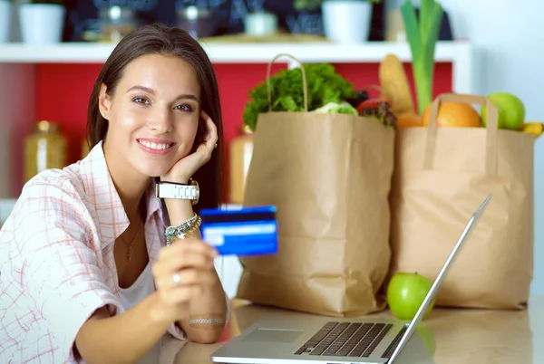 在厨房用平板电脑和信用卡给网上购物的女人微笑。微笑的女人 — 图库照片