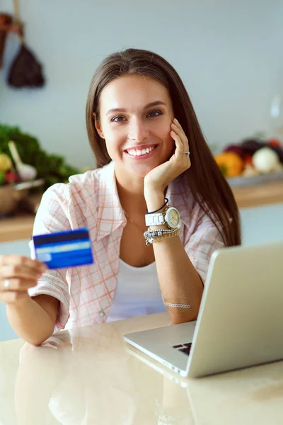 Mulher sorrindo compras on-line usando tablet e cartão de crédito na cozinha. Mulher sorridente — Fotografia de Stock