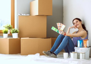 Kadın seçerek boya rengi renk örneği yeni ev ahşap yere oturmak için. Kadın evde