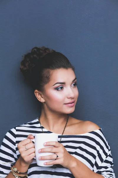 Young woman standing with cup, isolated on gray background. Young woman — Stock Photo, Image