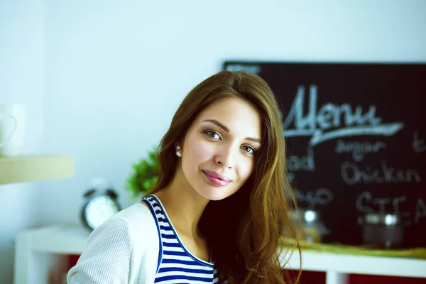 Jeune femme souriante tenant des légumes debout dans la cuisine. Jeune femme souriante — Photo