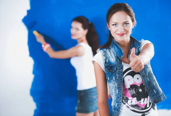 Two Young beautiful women holding color palette , standing near wall. Two Young beautiful women — Stock Photo, Image