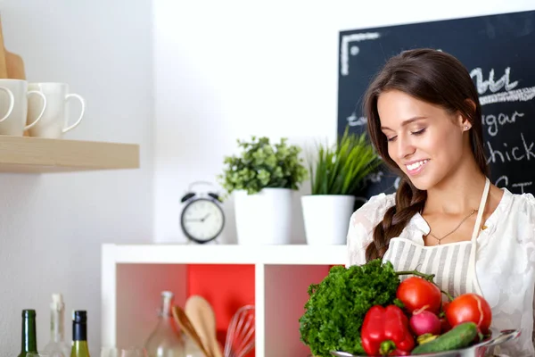 站在厨房里笑着拿蔬菜的年轻女人。微笑的年轻女人 — 图库照片