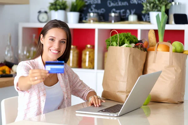 Mujer sonriente compras en línea utilizando tableta y tarjeta de crédito en la cocina. Mujer sonriente — Foto de Stock