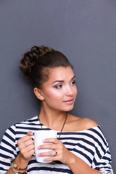 Young woman standing with cup, isolated on gray background. Young woman — Stock Photo, Image