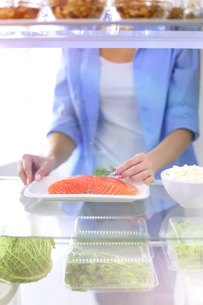 Retrato de una mujer parada cerca de una nevera abierta llena de alimentos saludables, verduras y frutas. Retrato de mujer — Foto de Stock