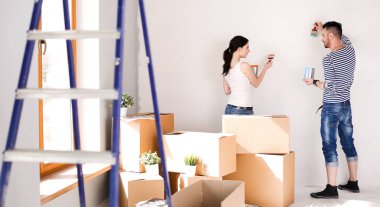 Yeni evin içini boyayan mutlu, genç bir çiftin portresi. Genç çift