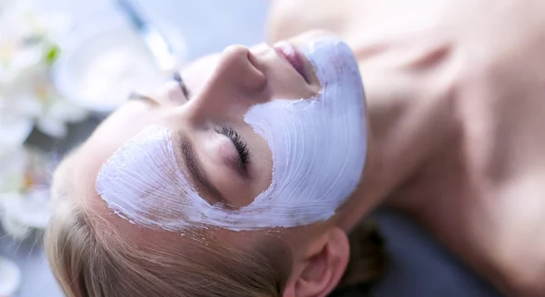 Mascarilla facial. Hermosa joven en el spa, mujer cosmética aplicando mascarilla facial — Foto de Stock