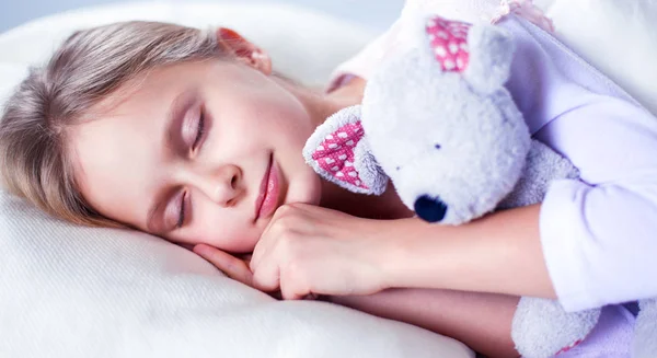 Bambino bambina dorme nel letto con un orsacchiotto giocattolo — Foto Stock