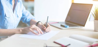 Ofis masasında dizüstü bilgisayarla oturan genç bir kadın. Genç bir kadın. Dizüstü bilgisayar