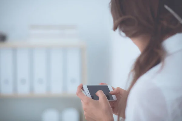 İş kadını ofiste akıllı telefonla mesaj gönderiyor. — Stok fotoğraf