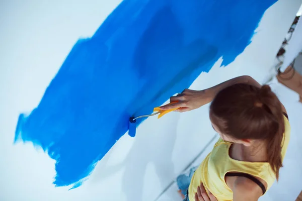 Feliz hermosa mujer joven haciendo pintura de pared, de pie cerca de la escalera —  Fotos de Stock