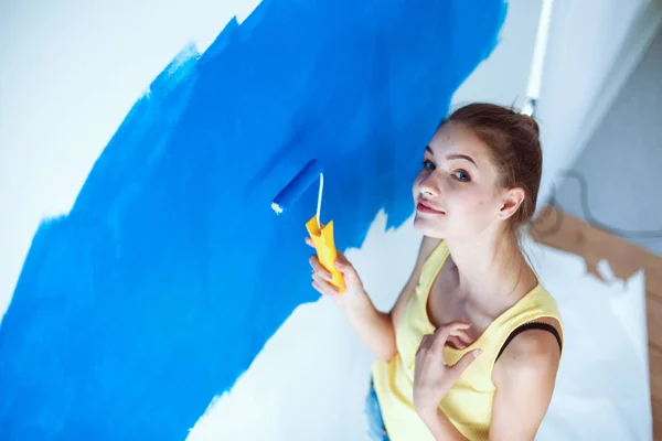 Счастливая молодая женщина, занимающаяся настенной живописью, стоящая рядом с лестницей — стоковое фото