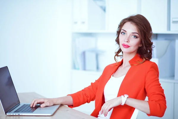 Mulher atraente sentada na mesa no escritório, trabalhando com computador portátil — Fotografia de Stock