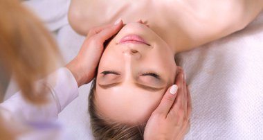 Masaj masasında uzanmış gözleri kapalı rahatlayan genç bir kadın. - Kadın. Spa salonu