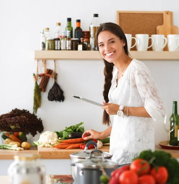 Mujer joven usando una tableta para cocinar en su cocina —  Fotos de Stock