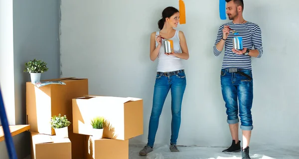 Portret gelukkig lachend jong koppel schilderij interieur wand van nieuwe huis — Stockfoto