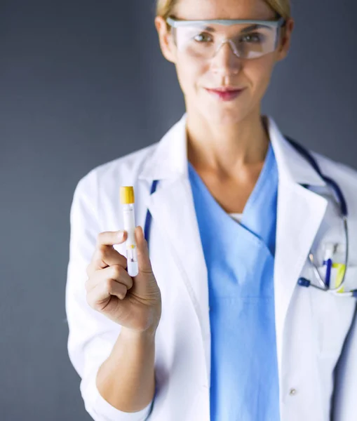 Medizinische oder wissenschaftliche Wissenschaftlerin oder Ärztin mit Blick auf ein Reagenzglas mit klarer Lösung in einem Labor oder Labor. — Stockfoto