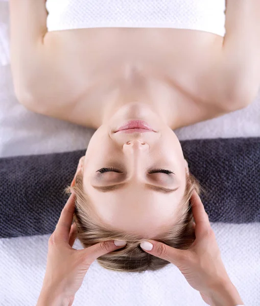 Mujer joven acostada en una mesa de masaje, relajándose con los ojos cerrados. Una mujer. Salón de spa —  Fotos de Stock