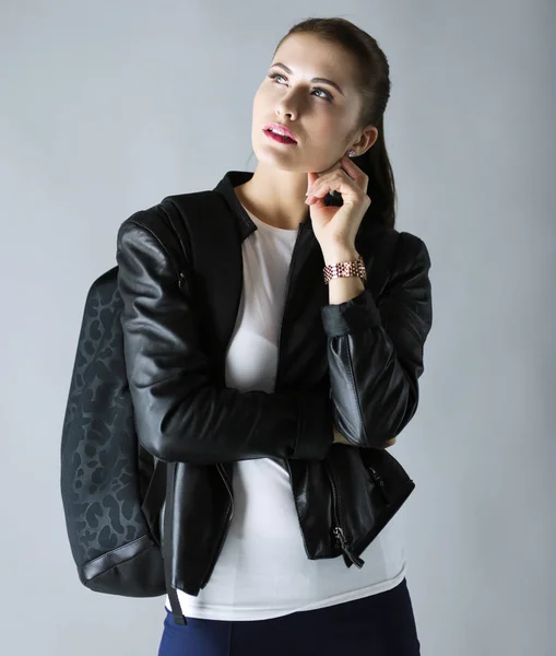 Портрет красивой юной брюнетки в стильной черной куртке на сером . — стоковое фото
