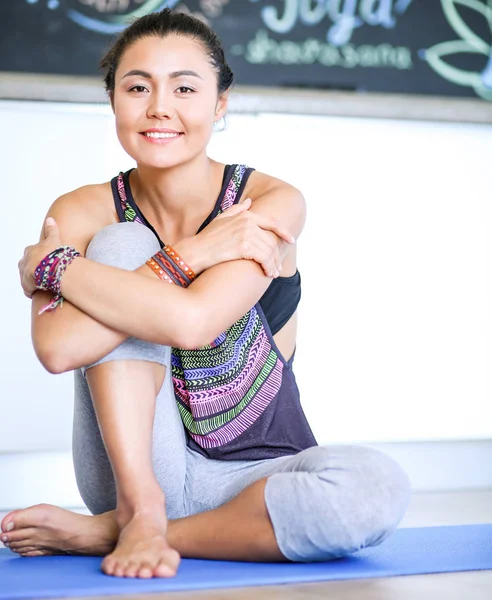 Retrato de una mujer sonriente de yoga sentada en la esterilla de yoga después del entrenamiento en el estudio de yoga. Yoga. Mujer. . — Foto de Stock