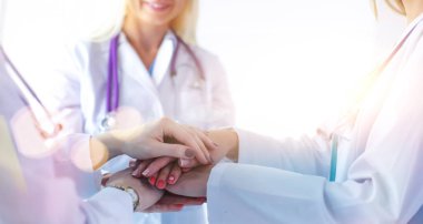 Doktorlar ve hemşireler tıbbi bir ekipte el ele tutuşuyorlar.