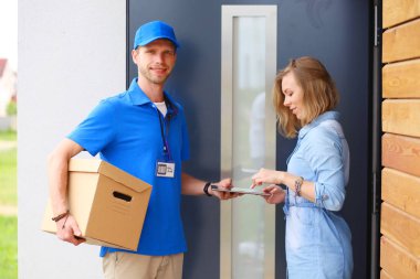 Mavi üniformalı gülümseyen kurye servis konseptine paket kutusu teslim eden teslimatçı. Mavi üniformalı gülümseyen teslimatçı.