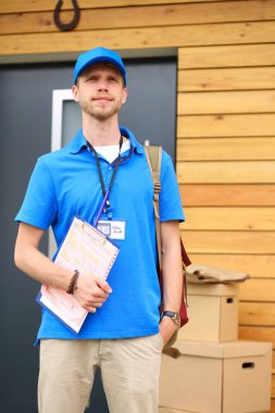 Mavi üniformalı gülümseyen kurye servis konseptine paket kutusu teslim eden teslimatçı. Mavi üniformalı gülümseyen teslimatçı.