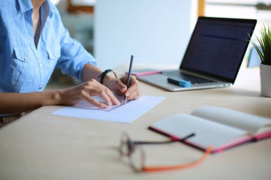 Ofis masasında dizüstü bilgisayarla oturan genç bir kadın. Genç bir kadın. Dizüstü bilgisayar