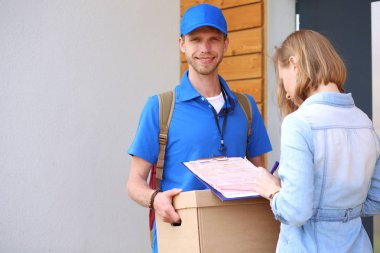 Mavi üniformalı gülümseyen kurye servis konseptine paket kutusu teslim eden teslimatçı. Mavi üniformalı gülümseyen teslimatçı.