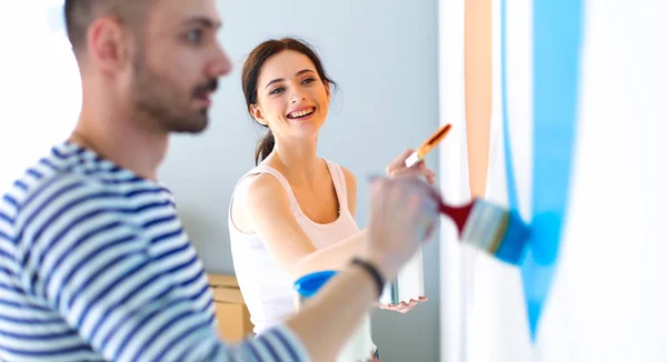 Ritratto di felice sorridente giovane coppia pittura parete interna della nuova casa — Foto Stock