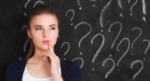 Young girl with question mark on a gray background — Stock Photo, Image