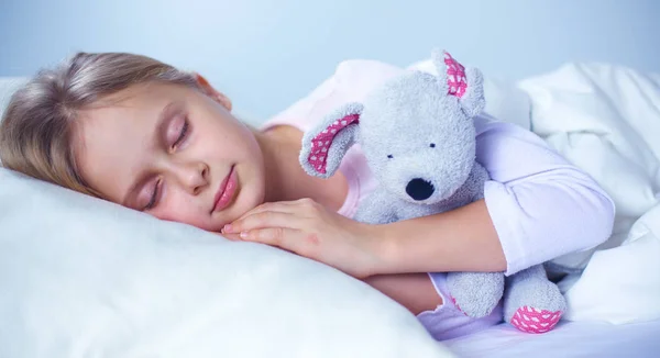 Παιδί κοριτσάκι που κοιμάται στο κρεβάτι με ένα αρκουδάκι παιχνίδι. — Φωτογραφία Αρχείου