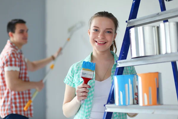 Ritratto felice sorridente giovane coppia pittura parete interna della nuova casa. Coppia giovane — Foto Stock