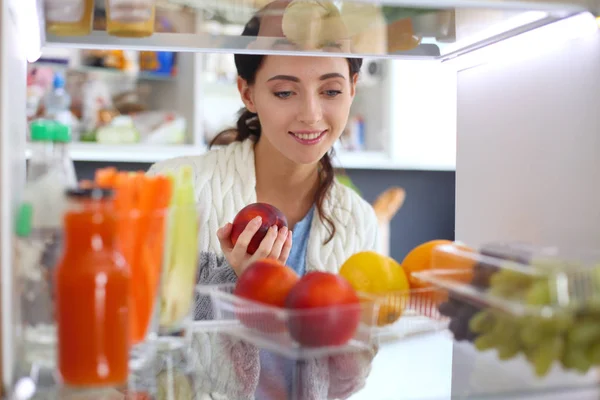 Portrait of female standing near open fridge full of healthy food, vegetables and fruits. Portrait of female — Stock Photo, Image