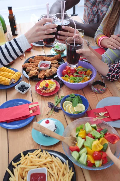 Vue du dessus du groupe de personnes qui dînent ensemble tout en étant assis à une table en bois. De la nourriture sur la table. Les gens mangent fast food. — Photo