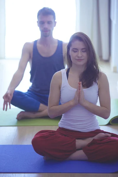 Hermosa pareja en ropa deportiva está meditando —  Fotos de Stock