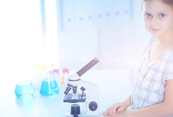 Schoolmeisje op zoek via Microscoop in de wetenschap klasse. — Stockfoto